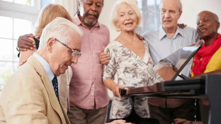The Power Of Music &Amp; Memory 1 A Diverse Group Of Senior Citizens Gather Together And Sing Around A Piano.